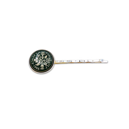 Silver plated hair slide with enamelled green sixpence coin design on a white background
