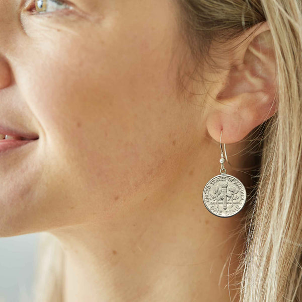 Close-up of a woman wearing a silver American Dime coin earring suspended on sterling silver ear wire.