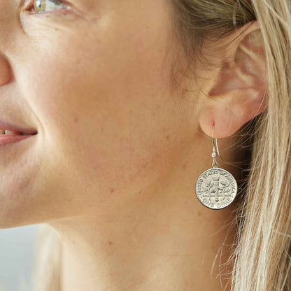 Close-up of a woman wearing a silver American Dime coin earring suspended on sterling silver ear wire.