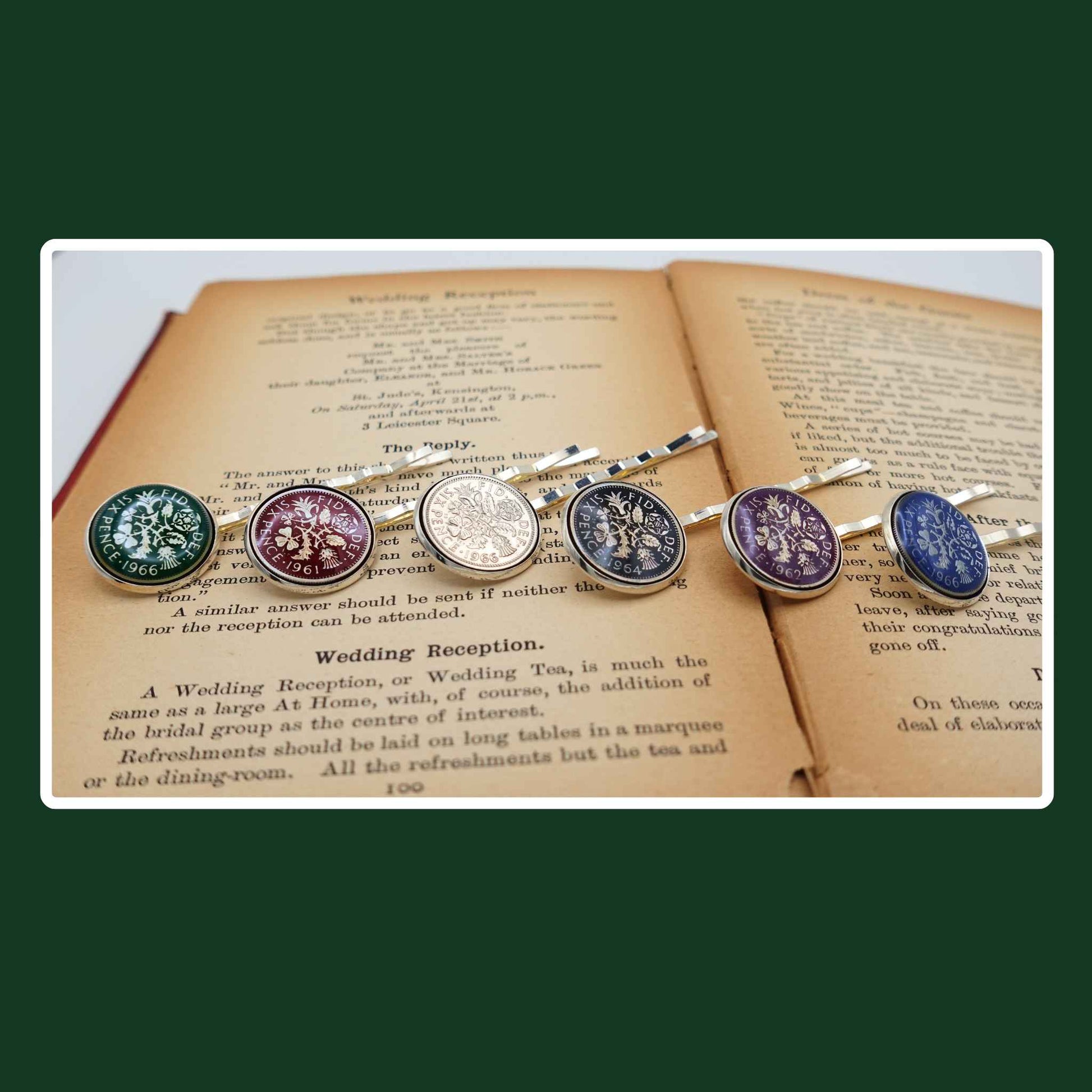 Set of decorative British sixpence coin coloured enamelled hair slides on an open book