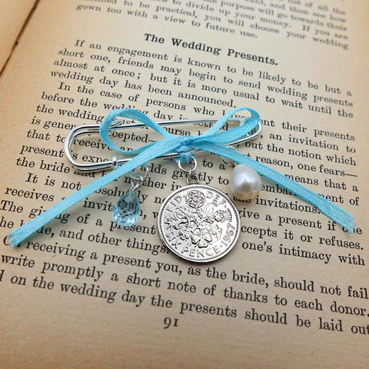 White freshwater pearl, blue topaz teardrop, genuine Queen Elizabeth 2nd sixpence coin with baby blue ribbon all suspended from a silver plated safety pin