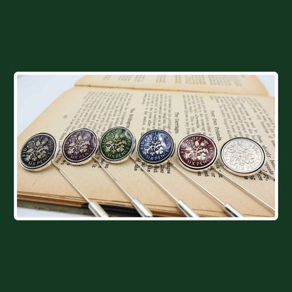 Set of six hand enamelled coloured British Queen Elizabeth 2nd sixpence coin silver plated tie pins with stoppers on book.
