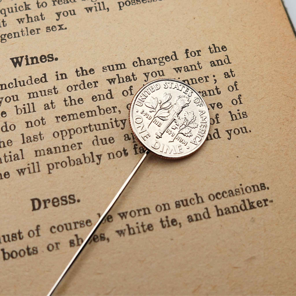 Silver US dime coin tie pin on a piece of paper with text