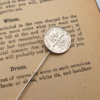 Silver US dime coin tie pin on a piece of paper with text