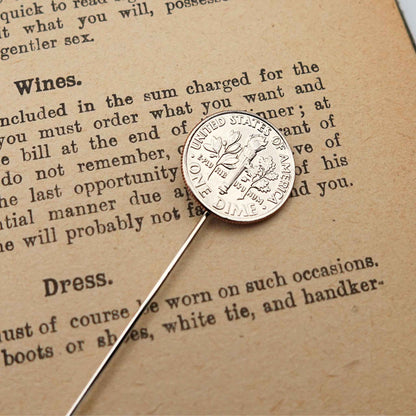 Silver US dime coin tie pin on a piece of paper with text