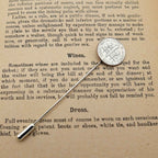 Silver American Dime coin tie pin on an old text document