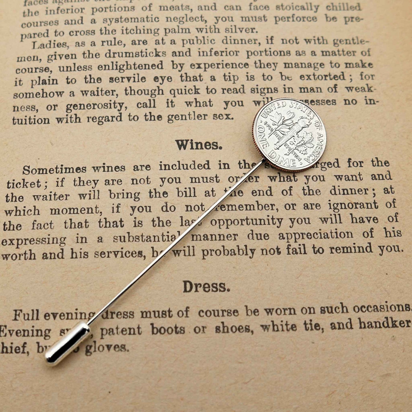 Silver American Dime coin tie pin on an old text document