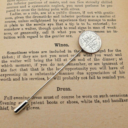 Silver American Dime coin tie pin on an old text document