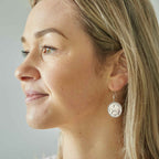 Close-up of a woman wearing a silver Irish threepence coin earring featuring a hare or rabbit animal with sterling silver ear wire.