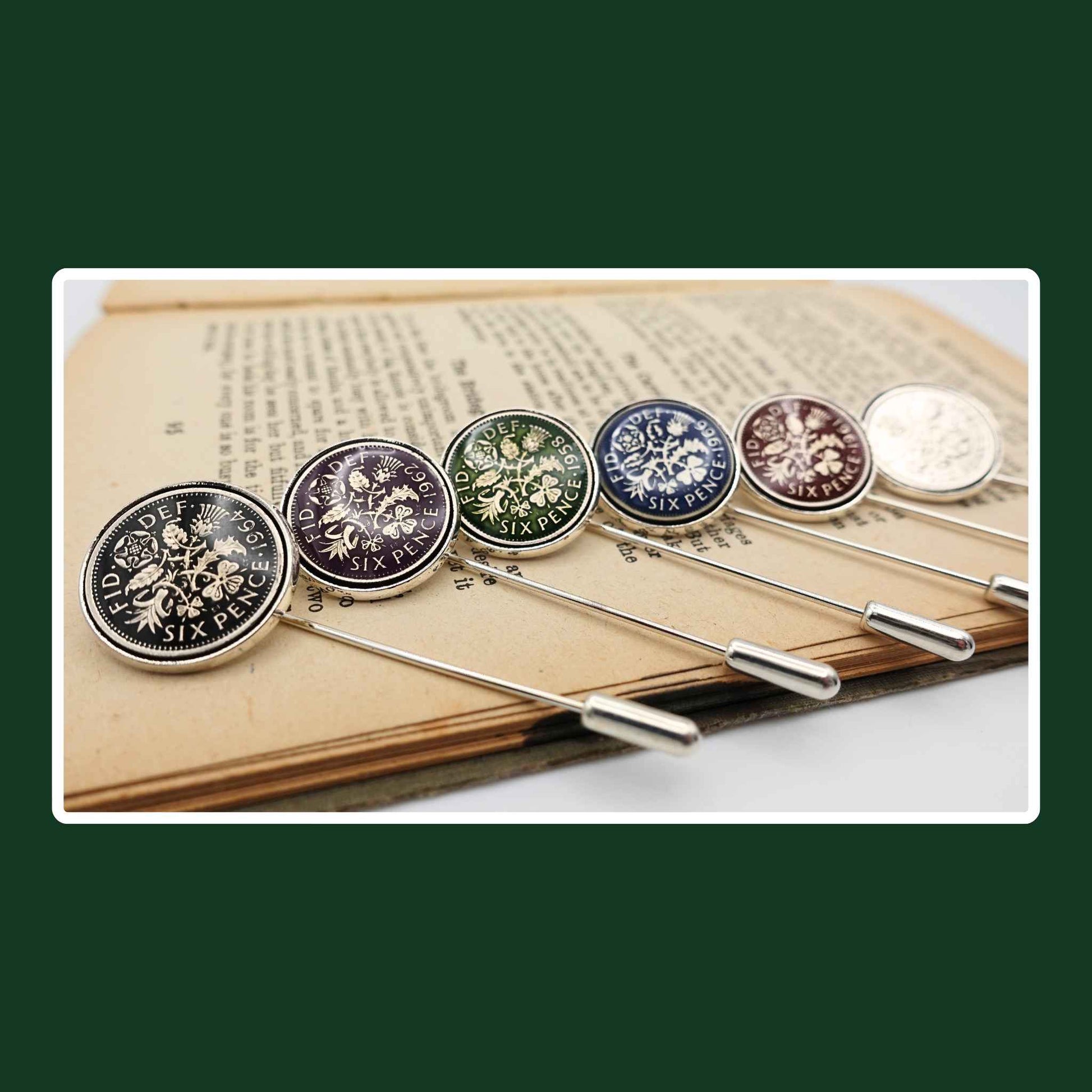 Set of six hand enamelled coloured british sixpence coin silver plated tie pins on book. 