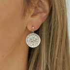Close-up of a person wearing an American Dime silver coin earring with a blurred background