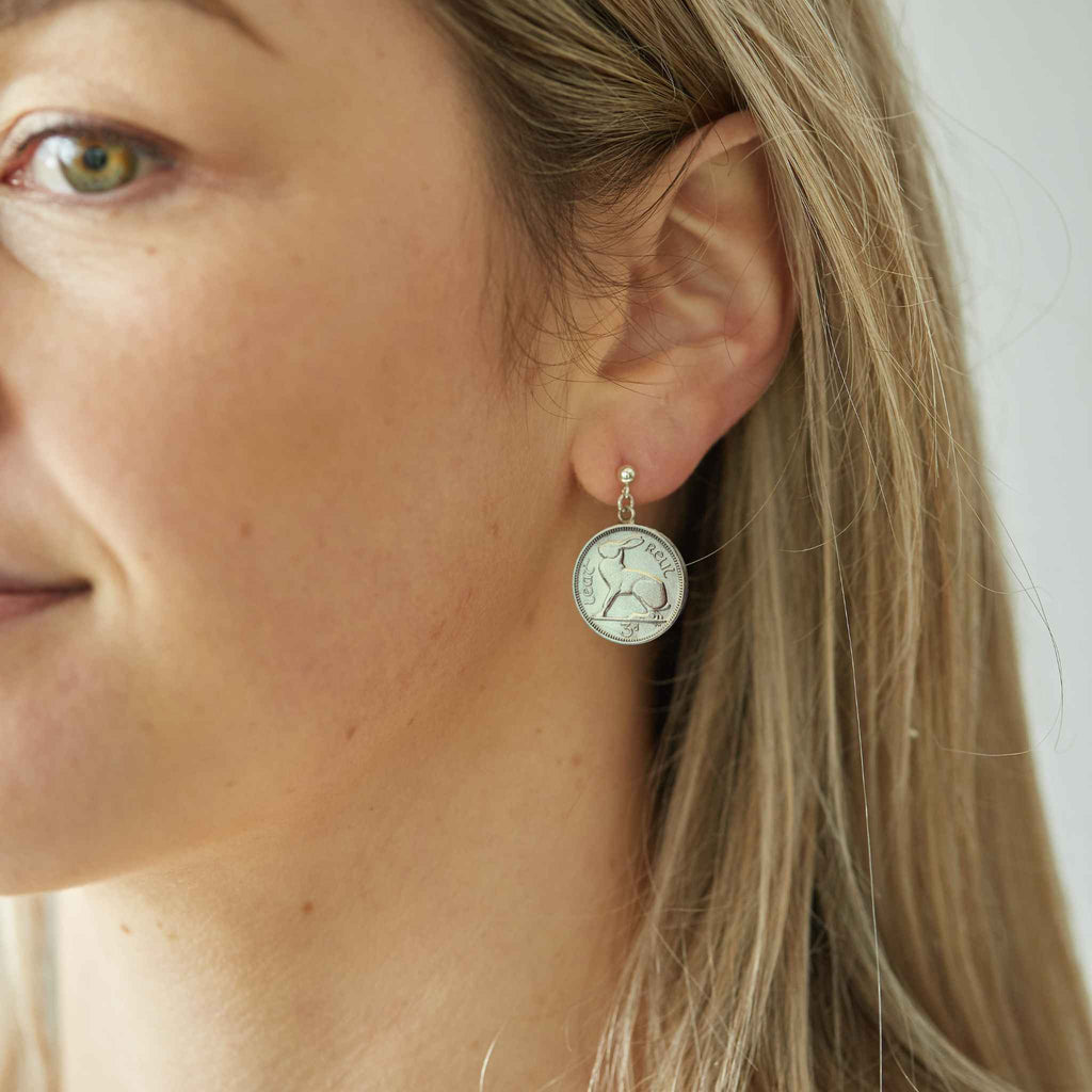 Close-up of a woman wearing a silver Irish threepence coin earring with sterling silver ear posts and butterfly backs.