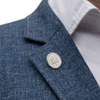 Close-up of a blue denim jacket with an American Dime coin lapel pin button and white shirt collar.