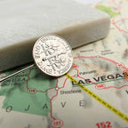 Silver dime coin tie pin on a map of Las Vegas