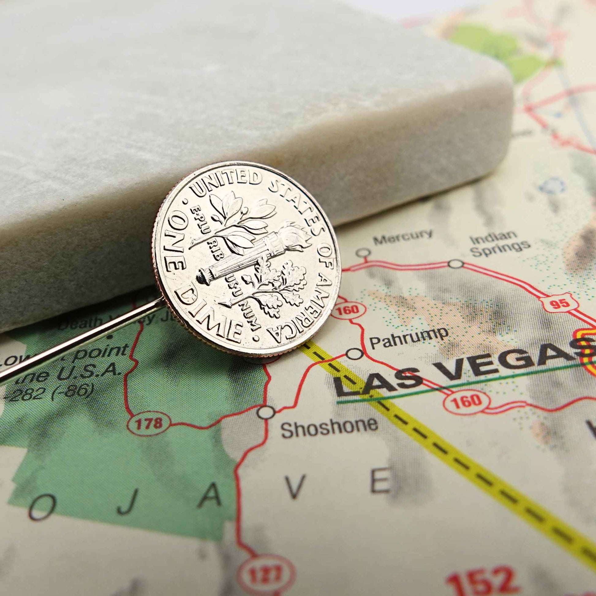 Silver dime coin tie pin on a map of Las Vegas