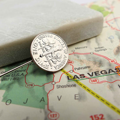 Silver dime coin tie pin on a map of Las Vegas