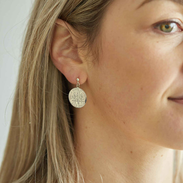 Close-up of a woman wearing an American Dime coin silver earring with sterling silver ear post.