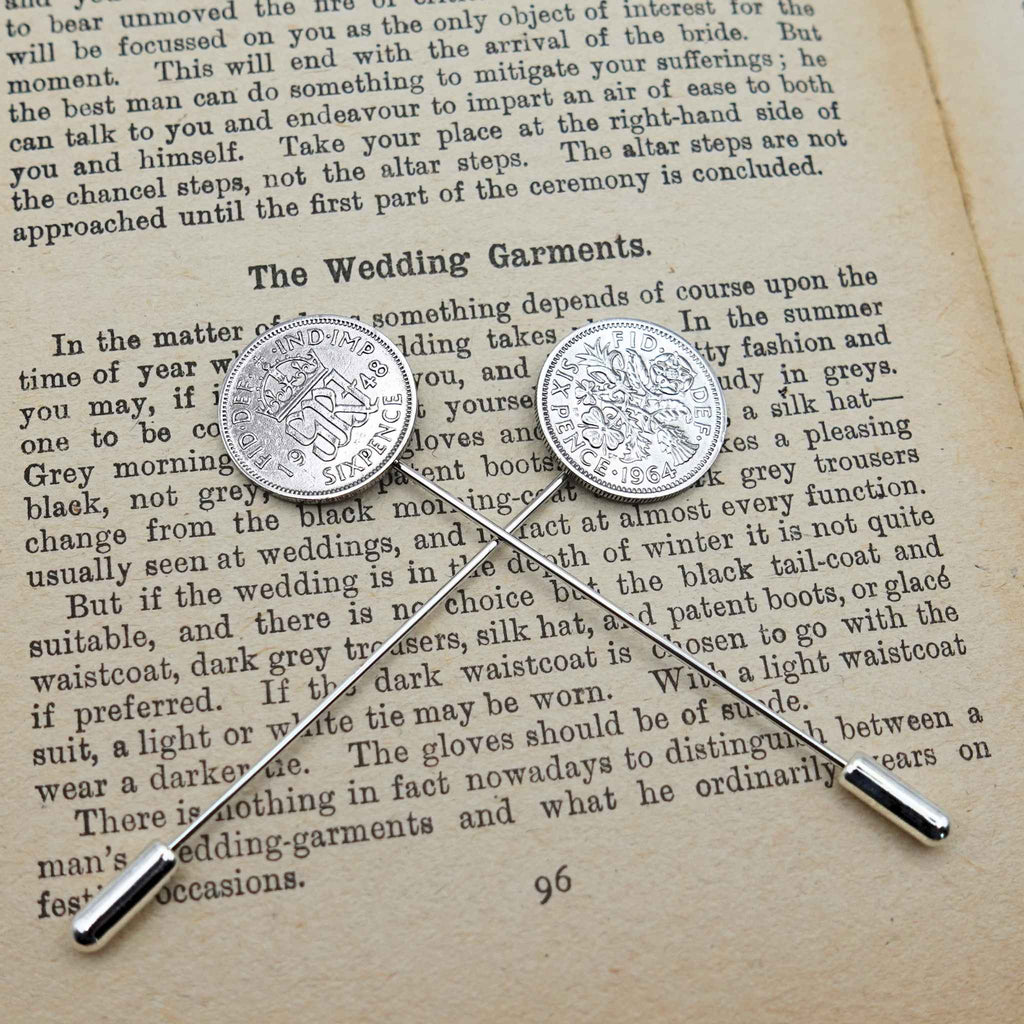 Two British Sixpence coin tie pins on an open book