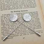 Two British Sixpence coin tie pins on an open book