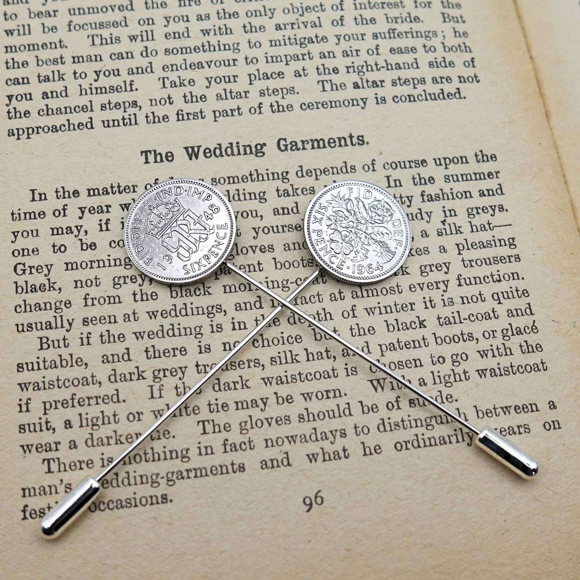 Two British Sixpence coin tie pins on an open book