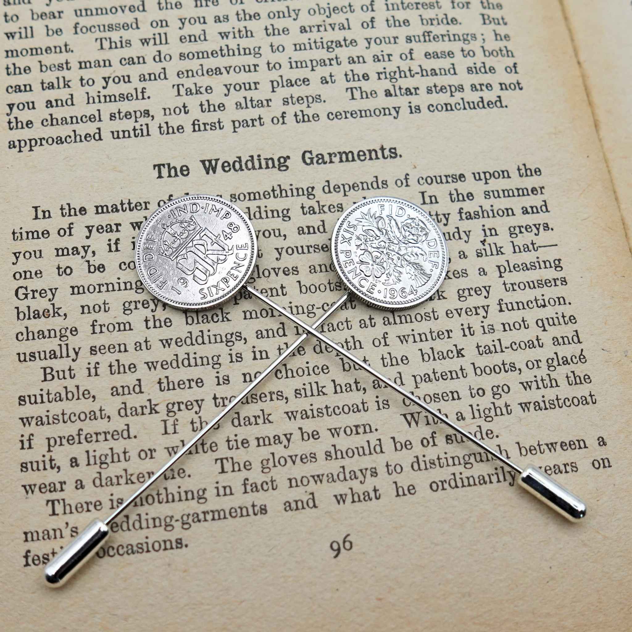 Two British Sixpence coin tie pins on an open book