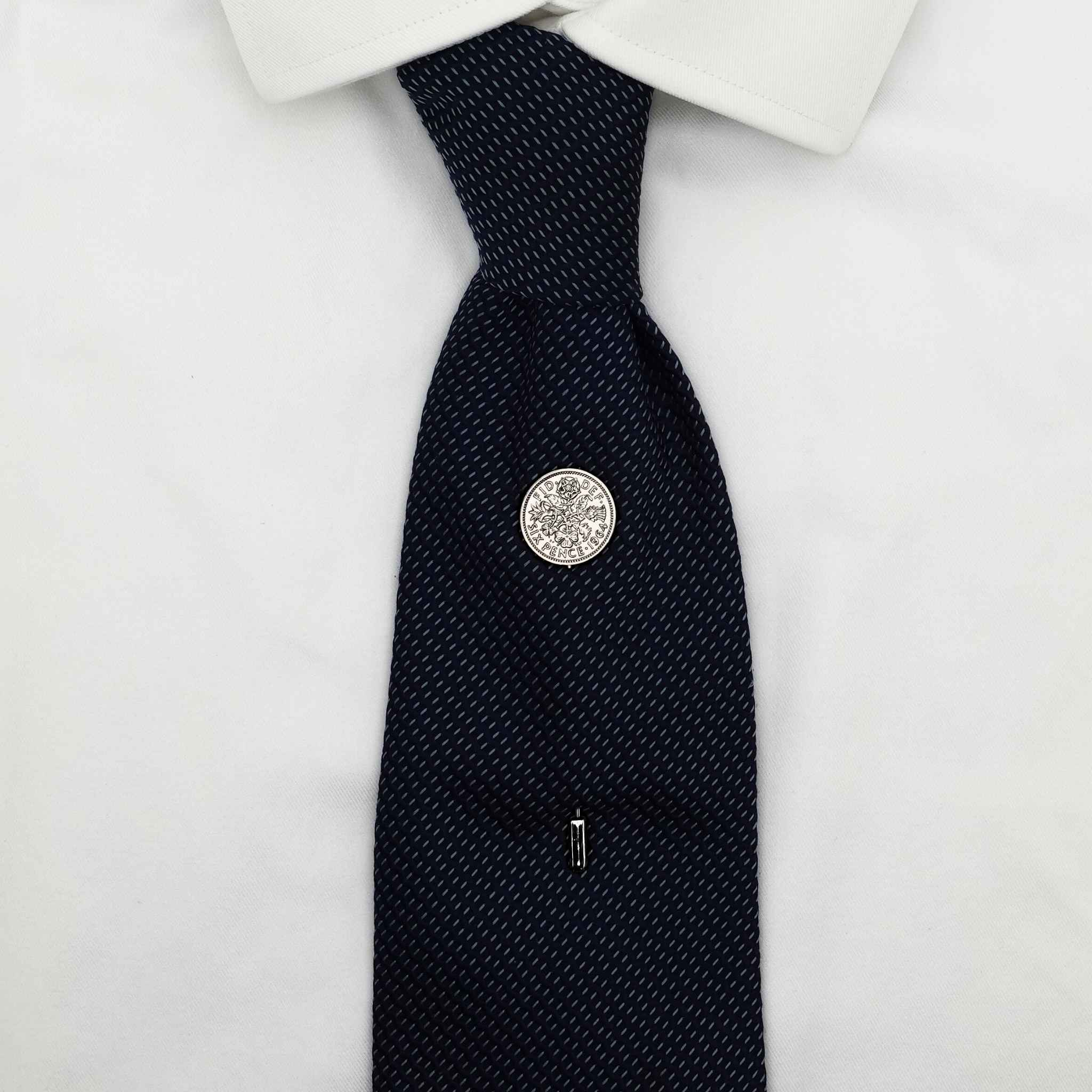 Navy tie on white shirt with Queen Elizabeth 2nd coin tie pin