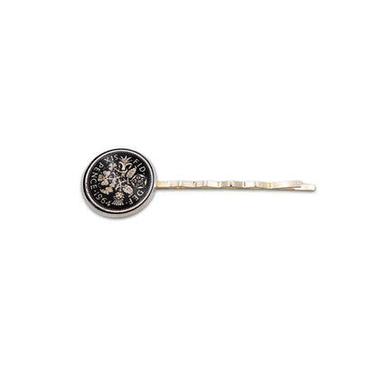 Silver plated hair slide with enamelled black sixpence coin design on a white background