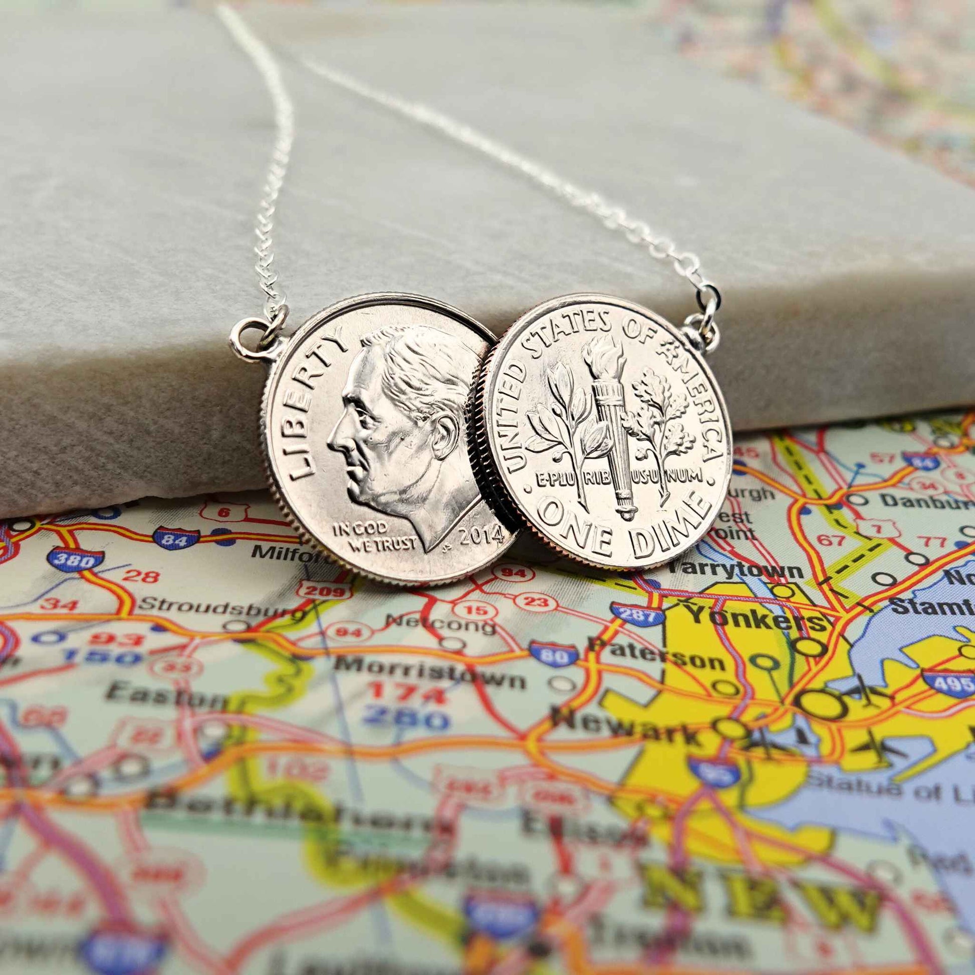 American Dime two coin necklace with sterling silver chain lying on a map