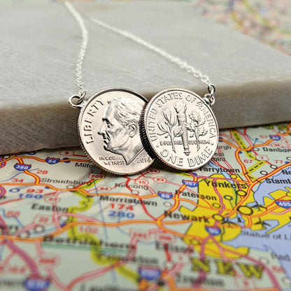 American Dime two coin necklace with sterling silver chain lying on a map