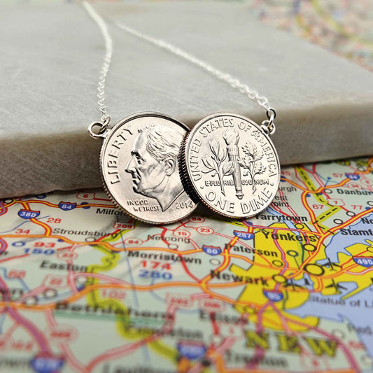 American Dime two coin necklace with sterling silver chain lying on a map