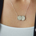 Silver necklace with two Irish threepence coins on a person's neck
