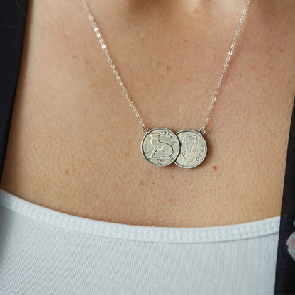 Silver necklace with two Irish threepence coins on a person's neck