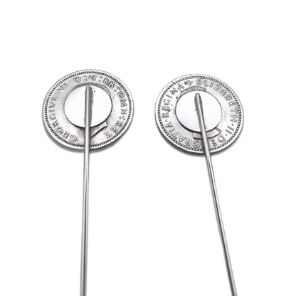 Two silver biritsh sixpence coin tie pins showing the backs on a white background