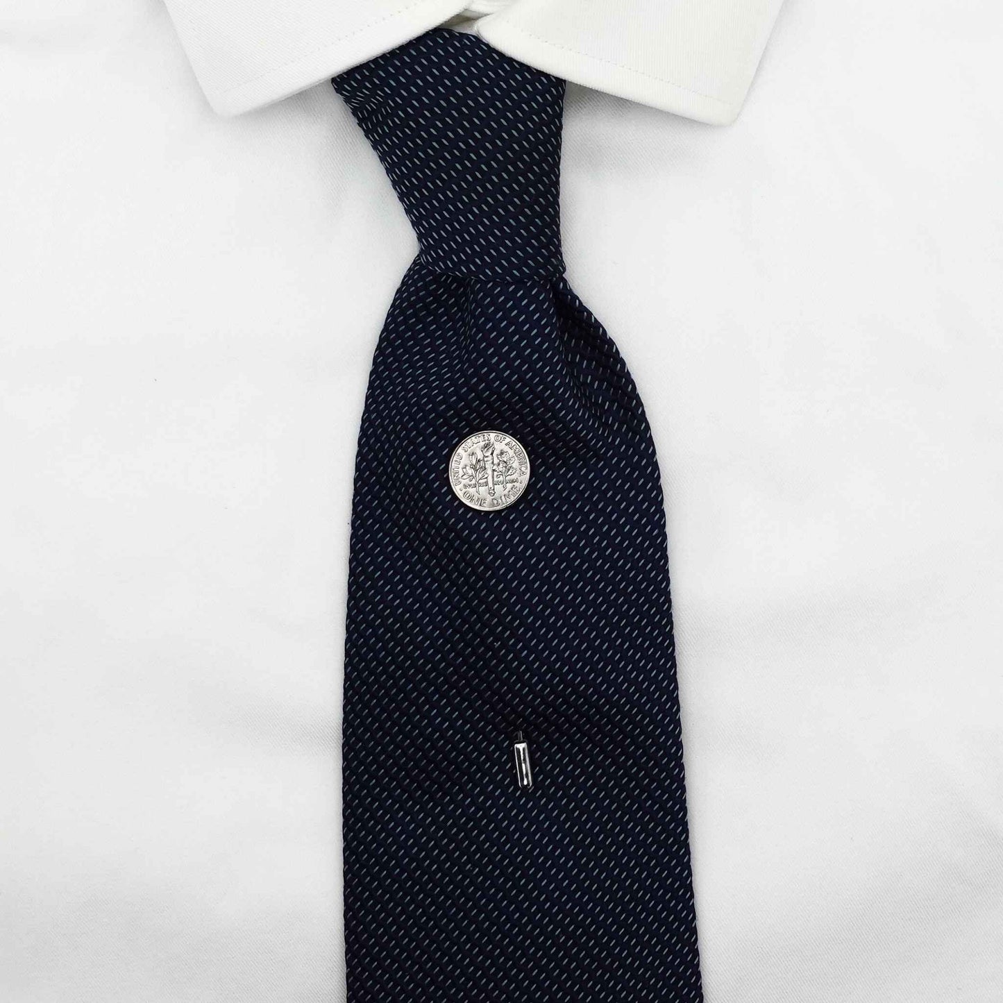 Navy patterned tie with a silver american dime coin tie pin on a white shirt
