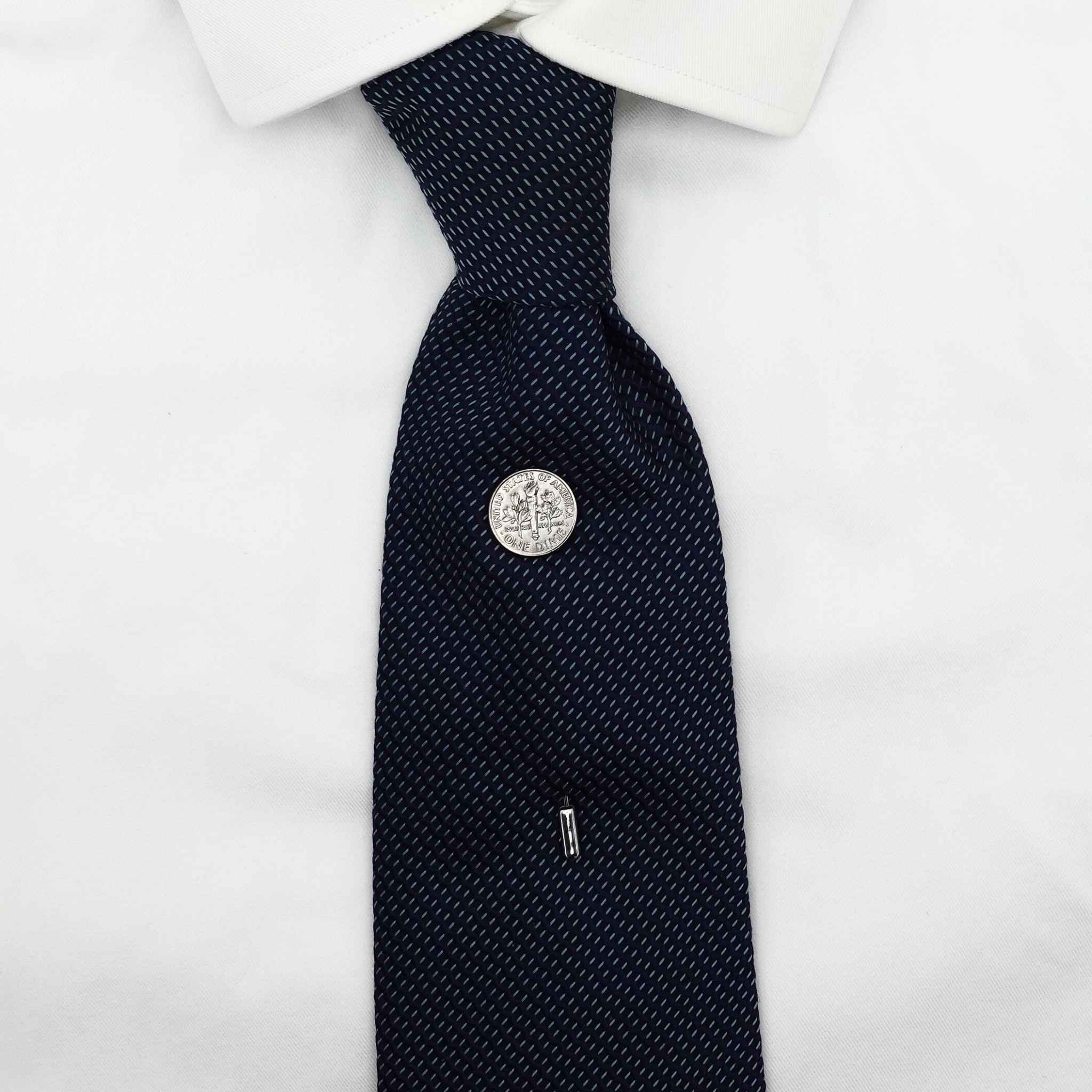 Navy patterned tie with a silver american dime coin tie pin on a white shirt