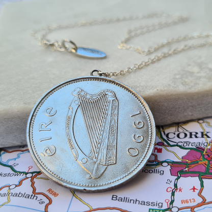 Silver Irish Punt coin necklace with harp design on a map background
