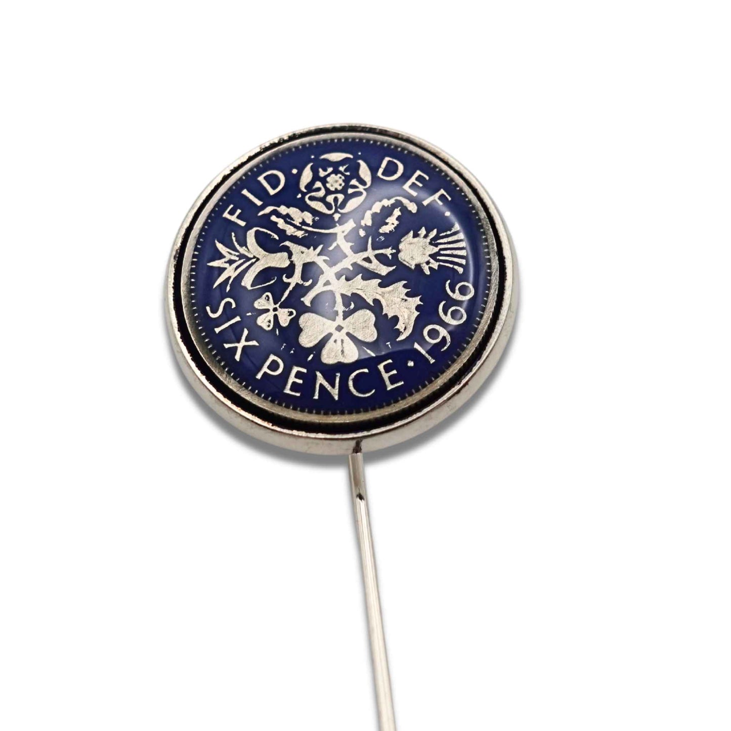 Close up of British sixpence coin with blue enamel set in silver plated tie pin on a white background