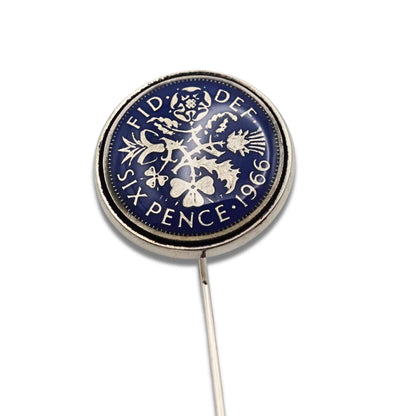 Close up of British sixpence coin with blue enamel set in silver plated tie pin on a white background