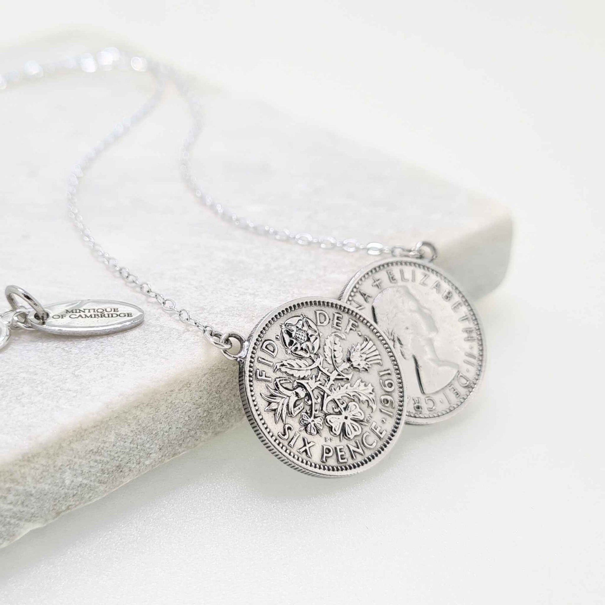Silver two coin sixpence necklace on a tile with white background