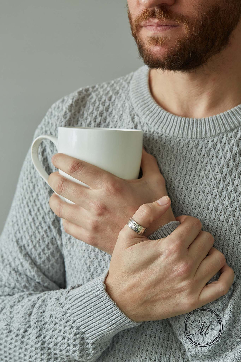 Half crown coin ring worn on thumb other hand holding a mug