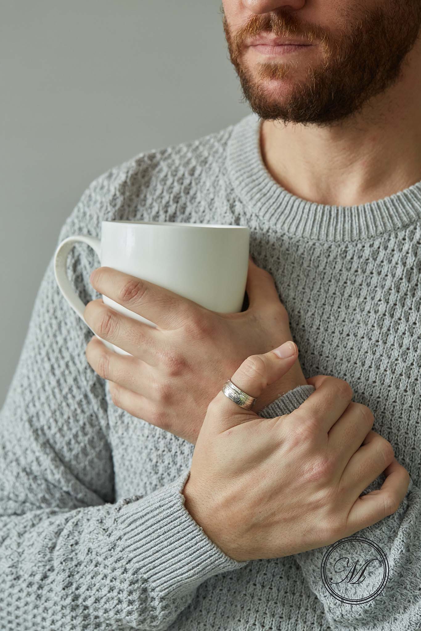 Half crown coin ring worn on thumb other hand holding a mug