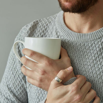Half crown coin ring worn on thumb other hand holding a mug