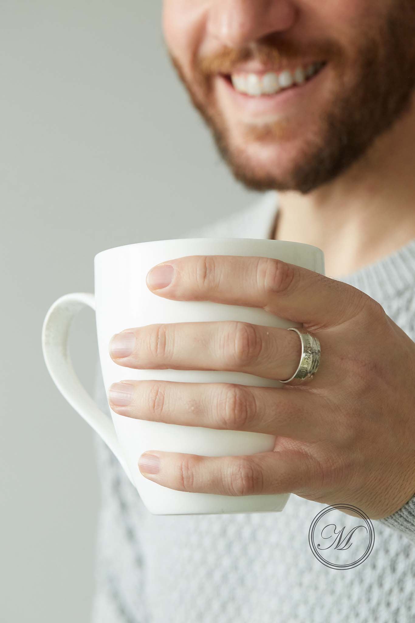 Half crown coin ring worn on middle finger holding a mug