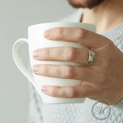 Half crown coin ring worn on middle finger holding a mug