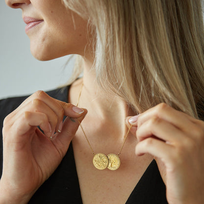 Woman adjusting a gold two coin sixpence necklace.